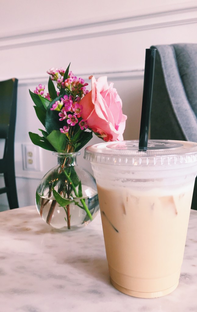Photo of iced coffee from Cavu Coffee. It is sitting on a marble table next to a vase of flowers